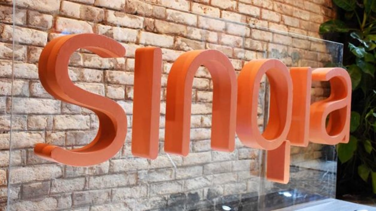 Imagem com a palavra 'Sinqia' escrita em letras laranjas. Ao fundo, uma parede de tijolos