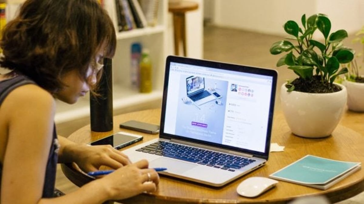 mulher escreve em papel com computador portátil em frente; profissão do futuro