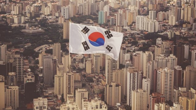 Montagem com bandeira da Coreia do Sul em em meio a prédios de São Paulo