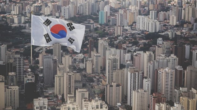 Montagem com bandeira da Coreia do Sul em em meio a prédios de São Paulo