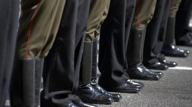 Pés de pessoas com sapato social e de militares com botas