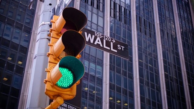 Foto de um semáforo com a luz verde no cruzamento de Wall Street; imagem ilustra os mercados acionários e o comportamento da bolsa e do Ibovespa