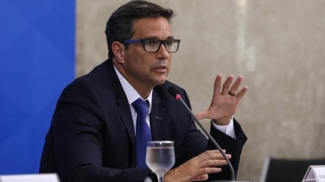 Presidente do Banco Central, Roberto Campos Neto, sentado em frente a um microfone