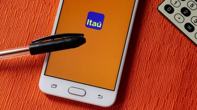 tela de celular com logotipo do itaú sob uma caneta