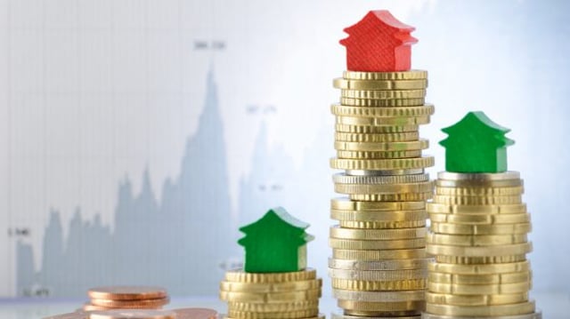 Imagem conceitual do mercado de fundos imobiliários (FIIs) mostra moedas empilhadas com miniaturas de casas REITs dividendos