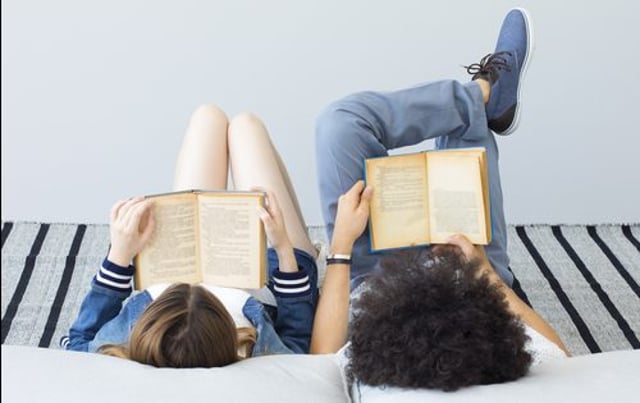 duas pessoas deitadas lendo livros
