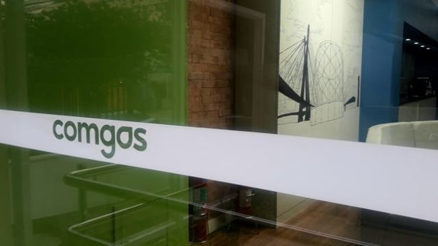 Imagem de uma porta de vidro com o logo da Comgás adesivado. A empresa faz parte da Compass, subsidiária da Cosan (CSAN3) que concentra os ativos de óleo e gás do conglomerado