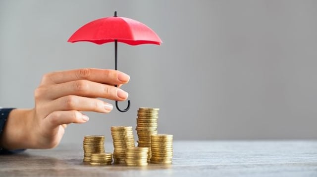 Imagem ilustrativa mostra guarda-chuva protegendo uma pilha de moedas, representando a inflação