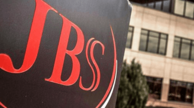 Imagem mostra a placa do frigorífico JBS (JBSS3) com um prédio ao fundo | Irmãos Batista dividendos