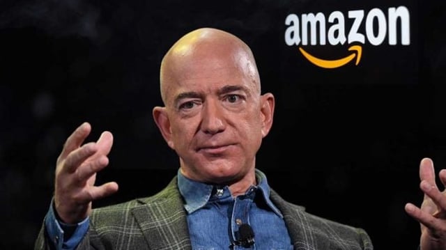 jeff bezos sentado com logo da amazon no fundo