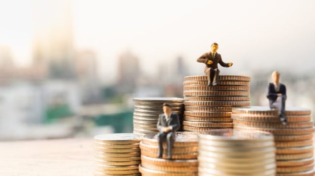 Bonecos em miniatura de homens vestidos de terno sentados em pilhas de moedas