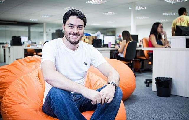 Victor Noda, CEO da Mobly, sentado em um pufe laranja no escritório