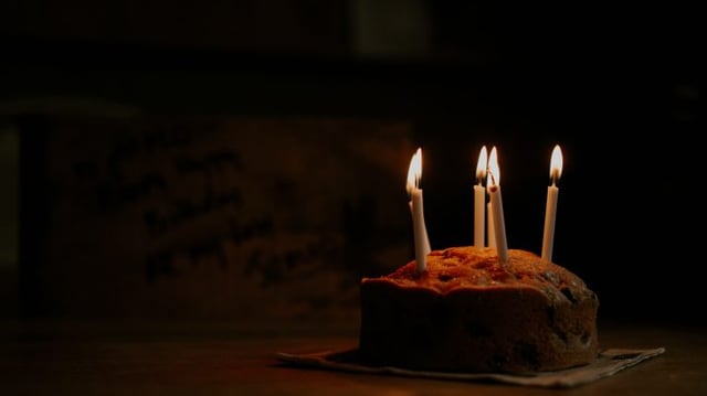 Bolo com quatro velas acessas em uma sala escura