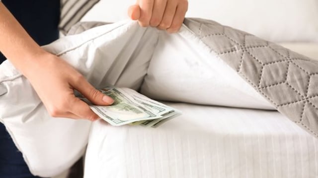 Pessoa colocando dinheiro embaixo de um cobertor | Venda coberta de ações