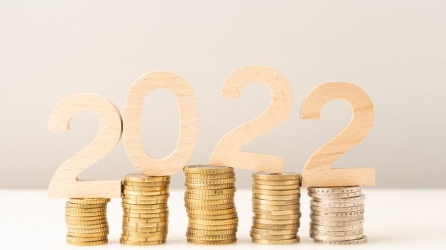 Números de madeira formando "2022" sobre pilhas de moedas