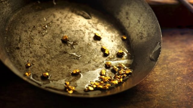 Imagem mostrando uma bacia com pequenos fragmentos de ouro, simbolizando a atividade do garimpo