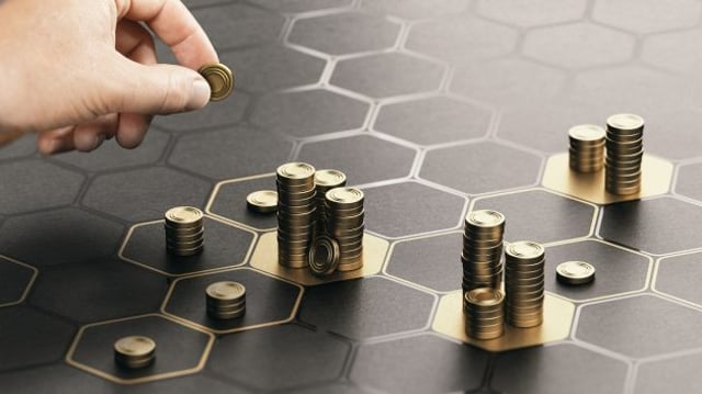 Imagem mostrando uma mão depositando moedas sobre um tabuleiro preto; representa o pagamento de proventos aos acionistas, como dividendos e juros sobre o capital Próprio (JCP) | Dividendos, fundos imobiliários, CVM, Maxi Renda, MXRF11