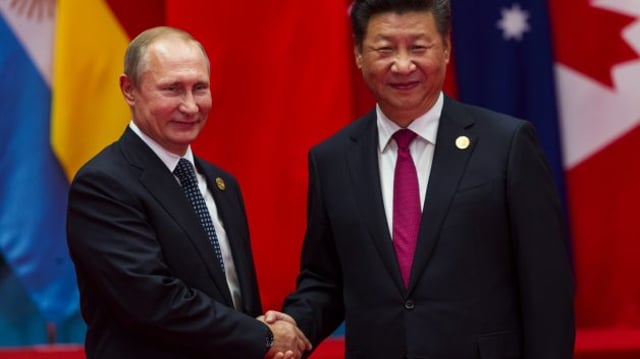 O presidente da Rússia, Vladimir Putin, cumprimenta com um aperto de mãos o presidente da China, Xi Jinping
