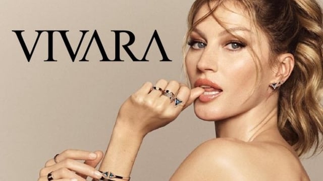 Campanha promocional da Vivara (VIVA3) com a modelo Gisele Bündchen. Ela olha em direção ao espectador, usando anéis e pulseiras de ouro e prata. Ao fundo, a palavra "Vivara" aparece em destaque