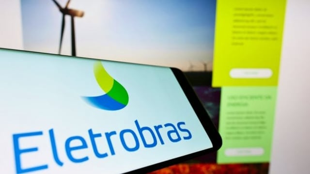 Celular com logo da Eletrobras na tela em frente ao site da empresa