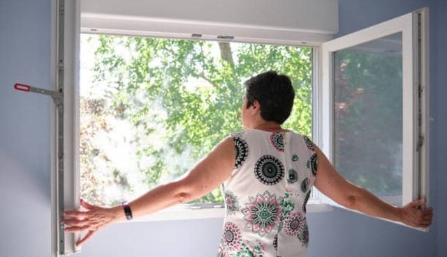 Woman opening the window to take a breath. Quarantine concept.