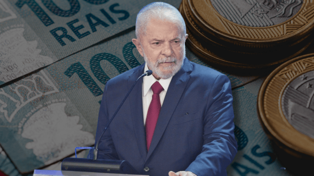 Lula veste terno azul e gravata vinho, de pé em um púlpito, com cédulas de real atrás