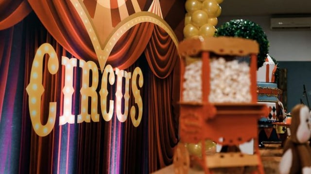 Cortina vermelha com dizeres Circus em dourado e carrinho de doces em primeiro plano