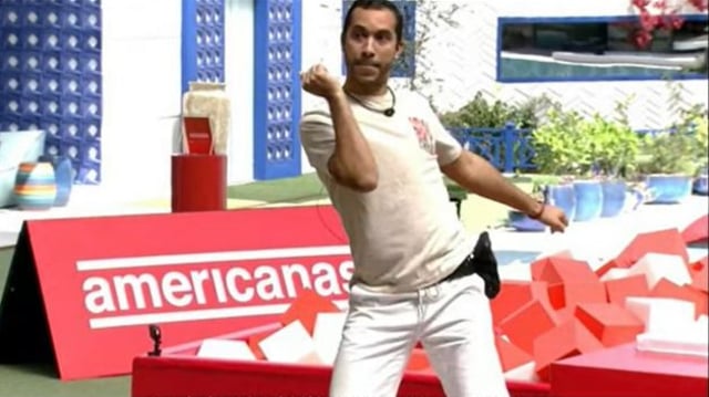 Gil do Vigor, participante do BBB, dança em frente a uma placa da Americanas (AMER3), uma das patrocinadoras do programa