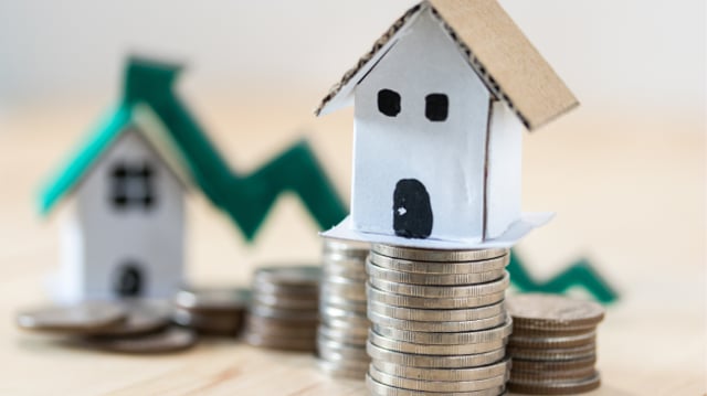 Miniaturas de casas sobre moedas representando os fundos imobiliários | fundo imobiliário DEVA11 dividendos