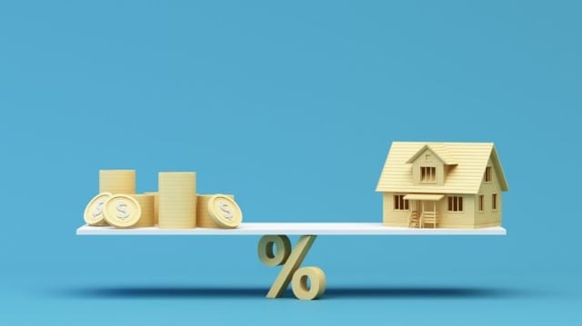 Miniatura de casa e moedas sobe uma balança sustentada pelo símbolo da porcentagem para representar o equilíbrio entre os dividendos, juros e fundos imobiliários