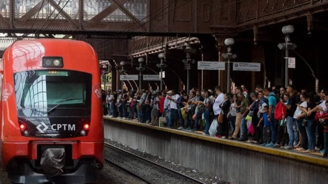 Imagem da estação de trem Luz, em São Paulo. Trem parado à esquerda. Plataforma, à direita, lotada com passageiros.