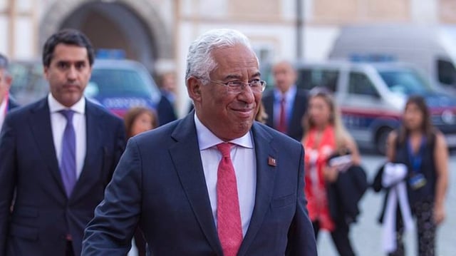 O primeiro-ministro de Portugal, António Costa, caminha na rua de terno azul escuro e gravata vermelha