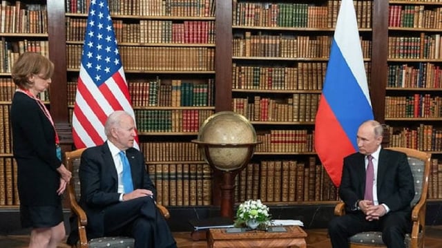 O presidente dos EUA, Joe Biden, e o presidente russo, Vladimir Putin, estão em uma sala, com uma grande estante cheia de livros ao junto e bandeiras dos EUA e da Rússia de cada ladp.