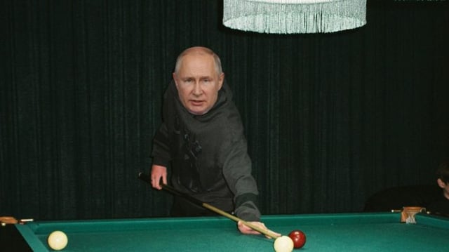 Um homem em uma mesa de bilhar, segura o taco entre as bolas branca e vermelha. Presidente russo, Vladimir Putin