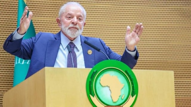 Fotografia do presidente Lula discursando em um púlpito com a imagem do continente africano