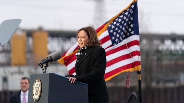 A vice-presidente dos EUA, Kamala Harris, está de pé, em frente a um púlpito, com a bandeira dos EUA atrás