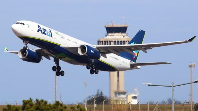 Avião da companhia de aviação Azul decolando, com torre de comando ao fundo