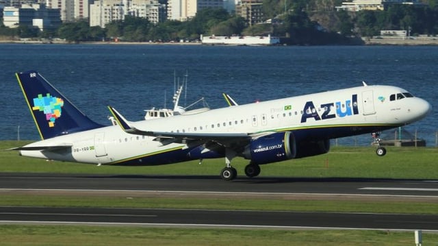 Avião da azul decolando, com mar ao fundo.