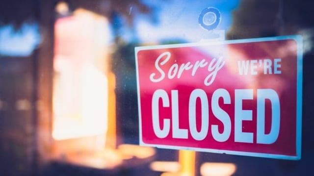 Janela fechada com placa "sorry, we are closed" em letras brancas e fundo vermelho