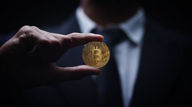 Homem segurando criptomoeda (bitcoin)