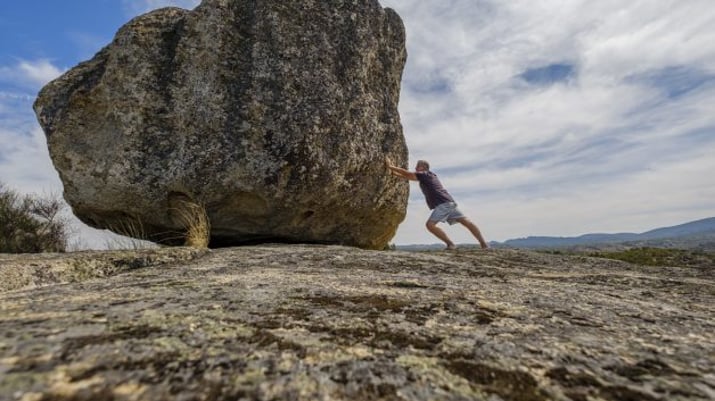 Homem empurrando uma rocha