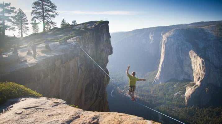 Homem cruzando uma corda bamba no mirante de Taft Point, no Parque Nacional Yosemite, na California