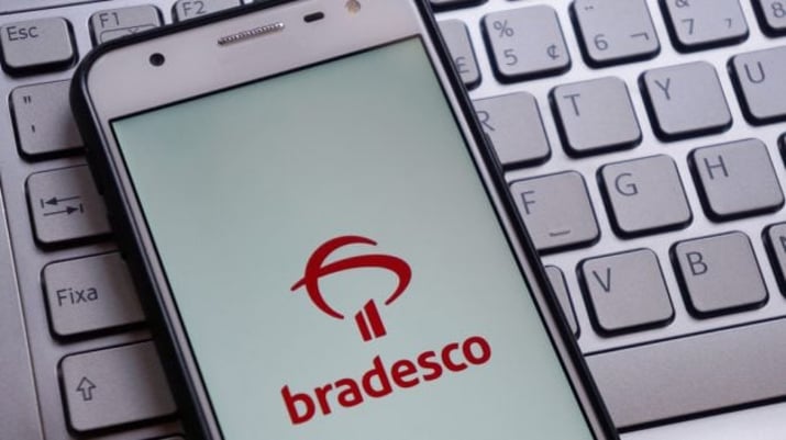 Telefone celular com tela do aplicativo do Bradesco sobre um teclado de computador Bradesco (BBDC4) dividendos