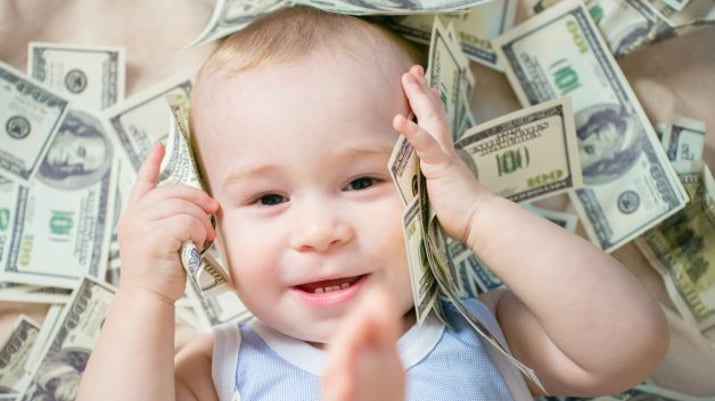 happy baby boy playing with a lot of money