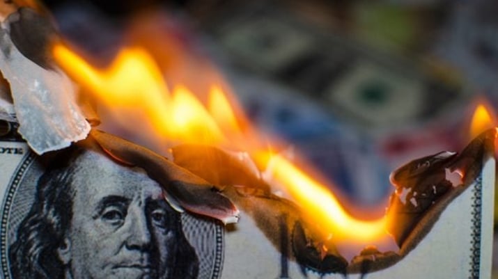 Nota de dólar queimando, simbolizando a inflação