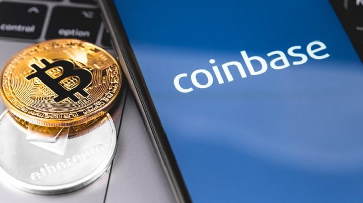 Logo da exchange Coinbase em tela de celular ao lado do símbolo do bitcoin