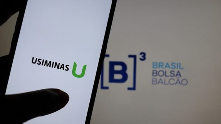 Logotipo da Usiminas em uma tela de celular com o logo da B3 ao fundo