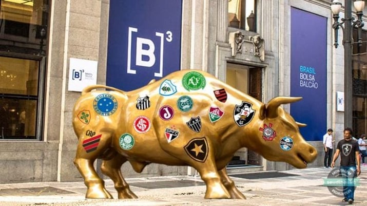 touro de ouro em frente à B3 com escudos de times de futebol, como Vasco