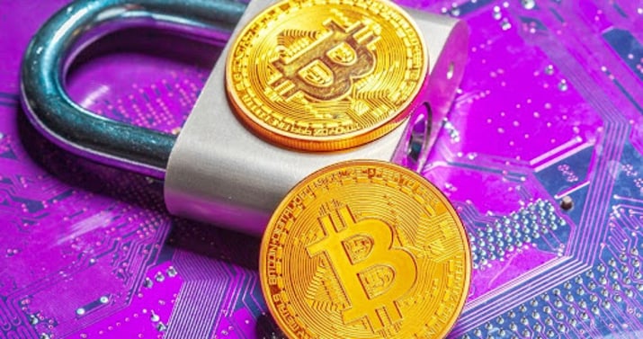 Um cadeado sobre fundo azul e duas moedas fictícias de Bitcoin. Criptomoedas.