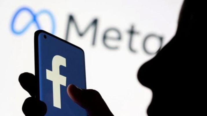 Imagem de celular com logotipo do Facebook e da Meta ao fundo